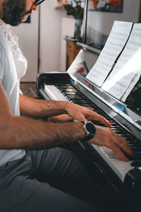Midsection of man playing piano by woman with notes
