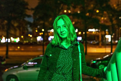 Portrait of a young woman in a night city in neon green on a summer evening. city lights.
