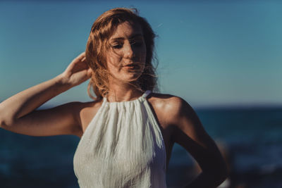 Young woman with hand in hair standing at beach