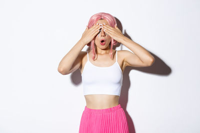 Portrait of woman with pink hair standing against white background