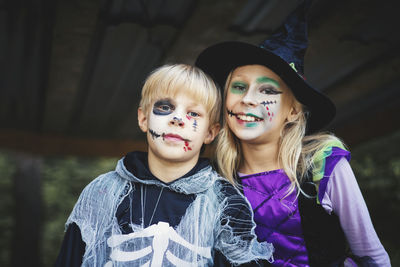 Portrait of smiling siblings in halloween costumes standing outdoors