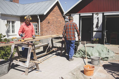 Senior couple doing carpentry at yard outside house