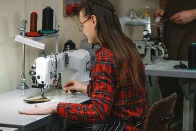 Woman sewing on professional sewing machine on the factory. tailor making accessories from eco