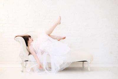 Woman lying on white wall