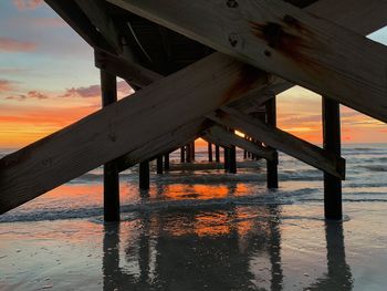 Pier over sea against sky during sunset