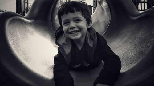 Close-up of smiling boy lying on slide at park