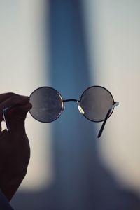 Close-up of hand holding sunglasses against blurred background