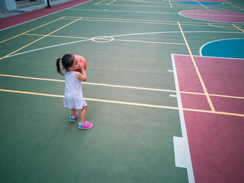 Full length of girl playing with basketball