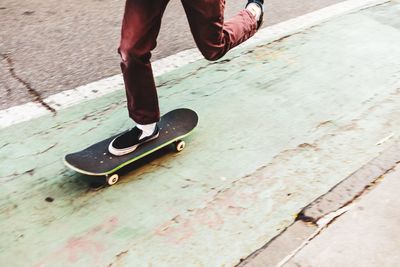 Low section of man skateboarding on footpath