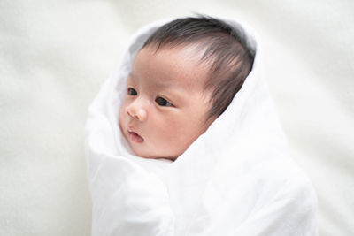 Portrait of cute baby girl lying on bed