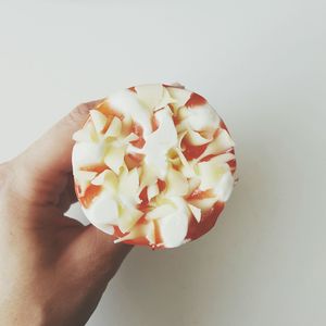 Close-up of hand holding flower over white background