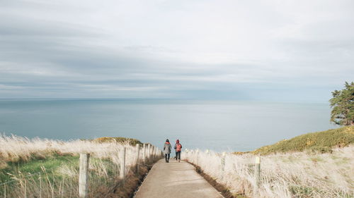 Rear view of men amidst sea against sky