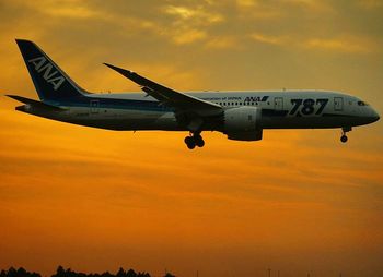 Airplane flying against sky at sunset