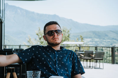 Portrait of young man wearing sunglasses against mountain