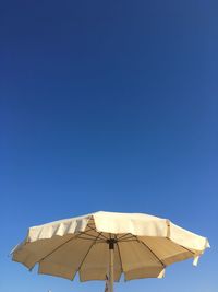 Low angle view of parasol against clear blue sky