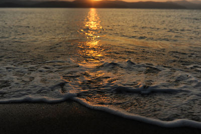 Abstract washed-out sea with wave and foam, shoreline in the sunset light, glare and bokeh.