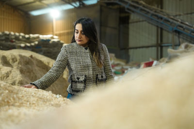 Woman inspecting biomass pellets at an industrial processing plant.