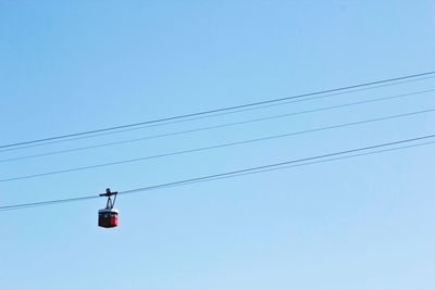 Low angle view of overhead cable car against clear blue sky