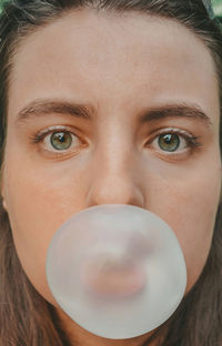 Close-up portrait of young woman blowing bubble
