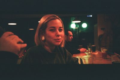 Portrait of woman looking at illuminated restaurant