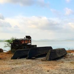 Abandoned ship on beach by sea against sky