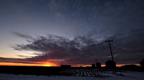 Silhouette houses against sky during sunset