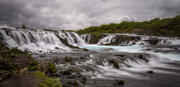Scenic view of waterfall against sky