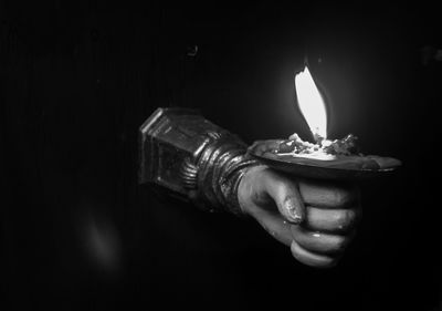 Close-up of hand holding burning candle