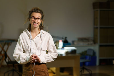 Young self-employed woman tailor business owner. happy seamstress with measuring tape in atelier