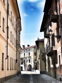 Alley amidst houses against sky in city