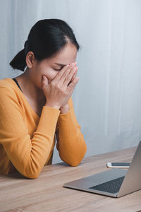 Young woman using mobile phone while sitting on table