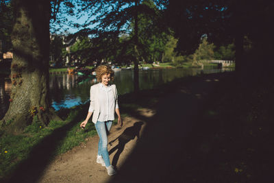 Full length portrait of woman standing by tree