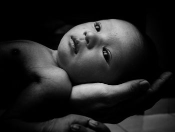 Close-up of mother hand holding cute baby on bed