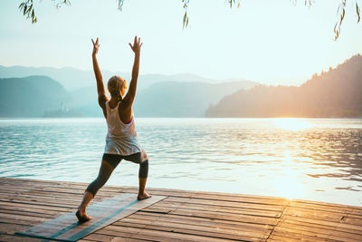 Full length of woman exercising on pier during sunrise