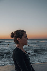 Woman on beach against sky during sunrise