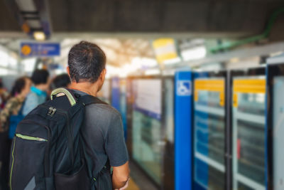 Rear view of man standing at railroad station