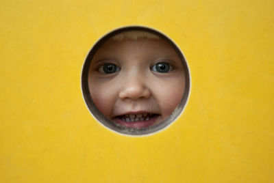 Portrait of cute smiling girl looking through hole