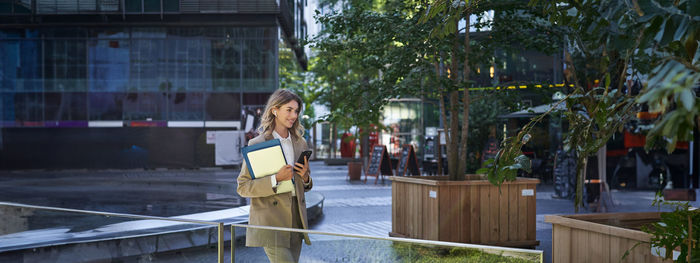 Side view of young woman standing against building