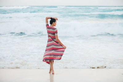 Rear view full length of young woman standing at beach