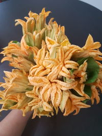 Close-up of hand holding fresh orange over black background