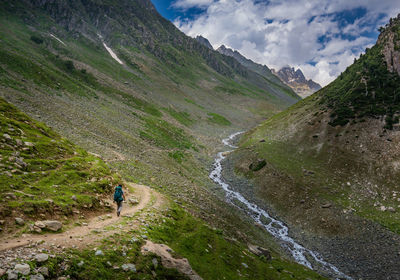 Person walking on field amidst mountains