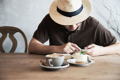 Man wearing hat sitting by coffee cup at restaurant