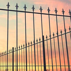 Low angle view of fence against sky during sunset