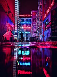 Reflection of people on illuminated building in city at night