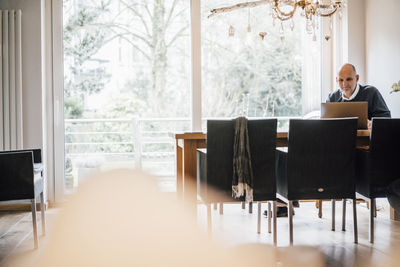 Senior man sitting at home, using laptop