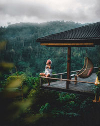 Woman sitting on railing in balcony