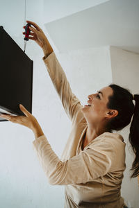 Happy woman fixing lighting equipment while renovating home