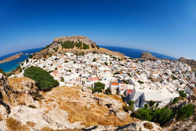 Scenic view of townscape by sea against clear blue sky