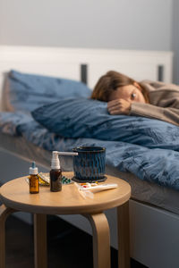 Selective focus on various pills, spray for a runny nose, thermometer and cup with hot beverage. 