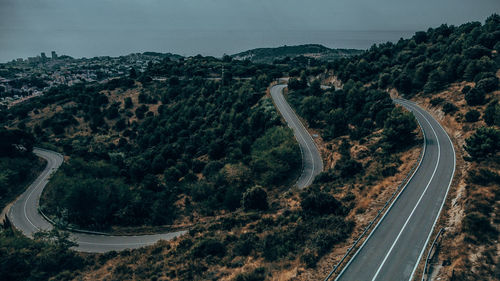 High angle view of winding road amidst trees against sky